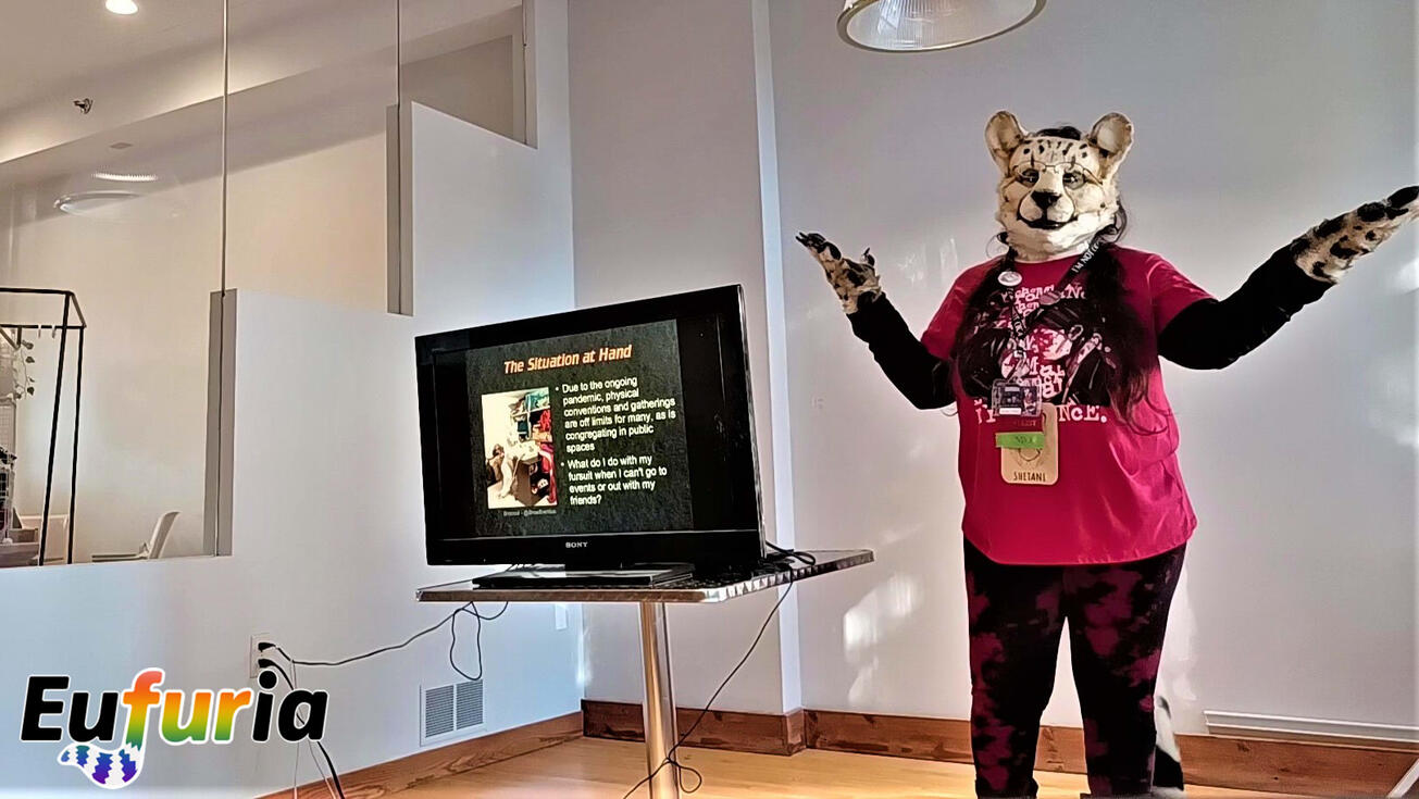 Speaker in cheetah fursuit giving a panel about at-home fursuiting